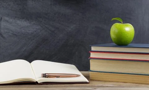 Rustic student desktop with green apple and study materials Stock Photos