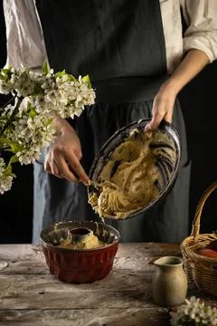 Rustic style apple bundt cake. Woman is filling cake form with dough. Woman b Stock Photos