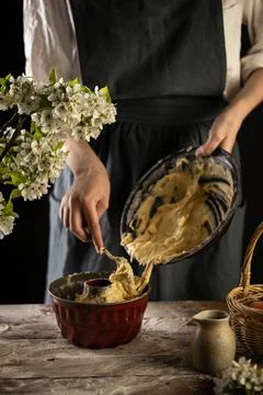 Rustic style apple bundt cake. Woman is filling cake form with dough. Woman b Stock Photos