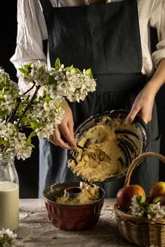 Rustic style apple bundt cake. Woman is filling cake form with dough. Woman b Foto stock