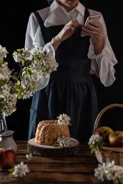 Rustic style apple bundt cake with powdered sugar. Woman makes photo of cake  Stock Photos