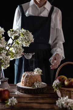 Rustic style apple bundt cake with powdered sugar. Woman sprinkles icing suga Stock Photos