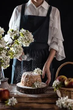 Rustic style apple bundt cake with powdered sugar. Woman sprinkles icing suga Stock Photos