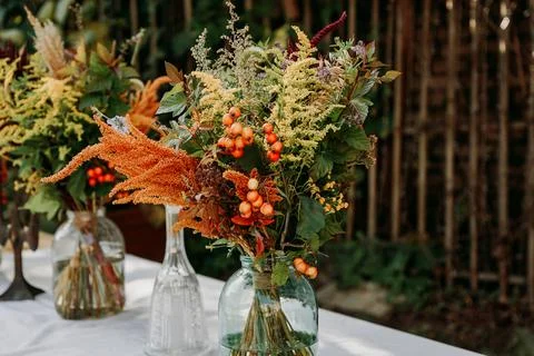 Rustic style bouquets on the table in glass vases and jars Stock Photos