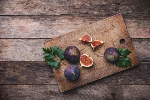 Rustic style cut figs on chopping board and wooden table Stock Photos
