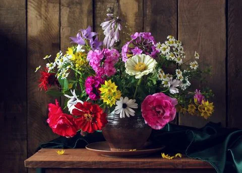 Rustic summer composition with a bouquet in a clay jug. Stock Photos