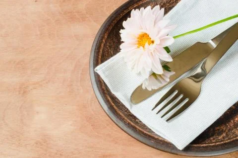 Rustic table setting with fresh flower, napkin and silverware. Stock Photos
