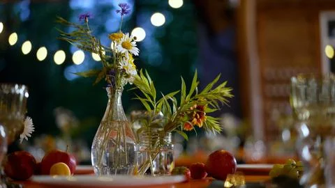Rustic table setting with wildflowers, fresh fruit, and warm string lights Stock Photos
