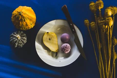 Rustic table still life. A plate with pear, macaroons, pumpkin, knife top view Stock Photos