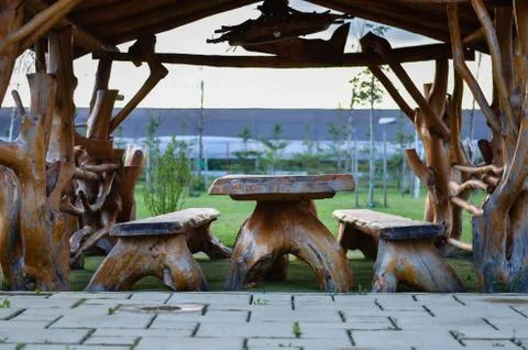 Rustic terrace with table and chairs made of natural wood parts in backyard . Stock Photos
