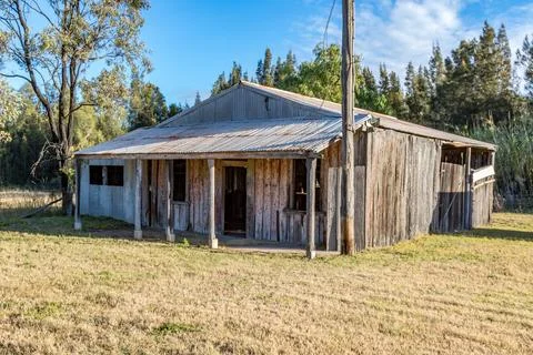 A rustic timber cabin stands weathered and worn in a quiet rural landscape Stock Photos