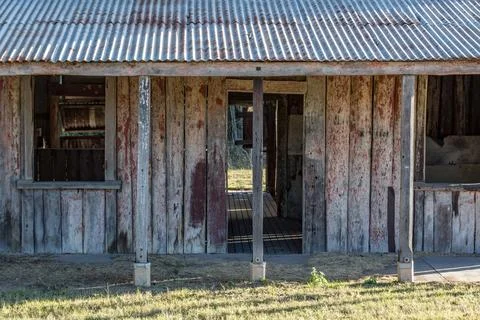 A rustic timber cabin stands weathered and worn in a quiet rural landscape Stock Photos