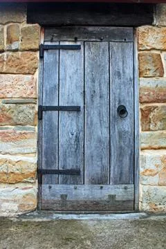 A rustic timber door with and aged textures set into a sandstone building Stock Photos