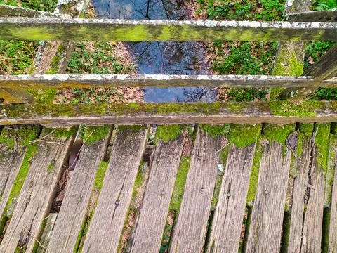 Rustic topdown view of a weathered wooden footbridge covered in lush green mo Stock Photos