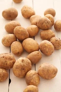 Rustic unpeeled potatoes on a table Stock Photos