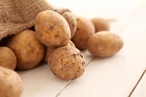 Rustic unpeeled potatoes on a table Stock Photos