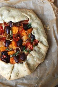 Rustic vegetable galette with roasted squash, tomatoes, and olives Stock Photos