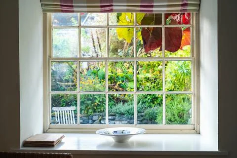 Rustic vintage sash window frame looking out to a lush English country garden Stock Photos