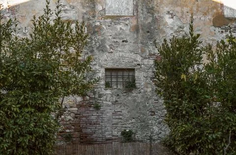 Rustic weathered stone wall with iron window and exposed brickwork in histo.. Stock Photos