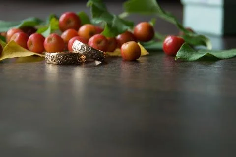 Rustic wedding decorations. Red small apples and gold rings on a wooden bac.. Stock Photos