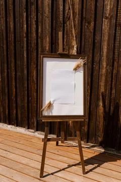 Rustic Wedding Easel with Blank Paper, Pampas Grass, and Wooden Barn Backdr.. Stock Photos