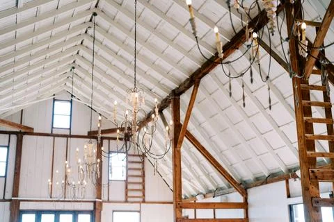 Rustic white barn interior with chandeliers and wooden beams Stock Photos