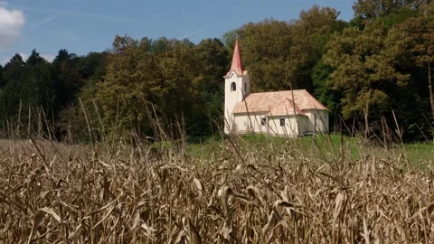 Rustic white chapel with a red roof sits peacefully on a lush green hill, skies. Видео 285772896