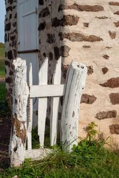 Rustic white garden gate by colonial stone building. Stock Photos