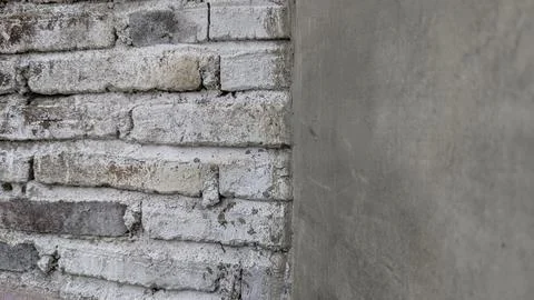 Rustic white-washed brick wall meets smooth concrete: Contrasting textures Stock Photos