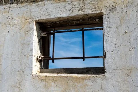 Rustic window frame revealing blue sky through its barred aperture Stock Photos