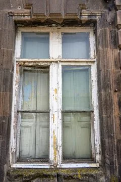 Rustic window framed in cracked stone, glass panes faded and aged Stock Photos