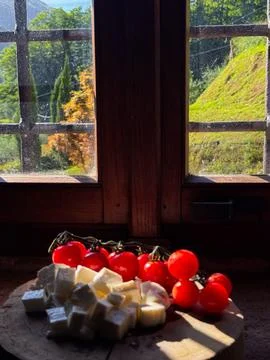 Rustic window view with tomatoes and cheese snack Stock Photos
