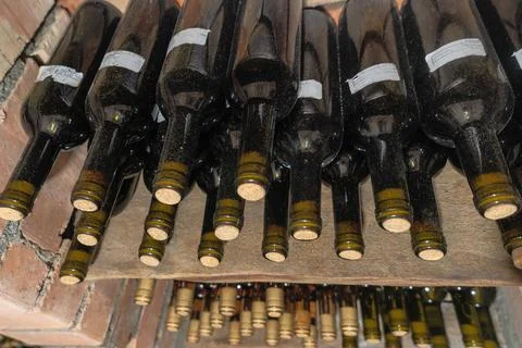 Rustic Wine Cellar Filled With Aging Bottles On Wooden Shelves. A Detailed .. Stock Photos
