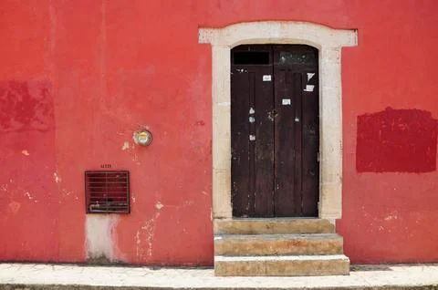 Rustic wood door in red wall, white stone trim, colonial Valladolid charm Foto stock