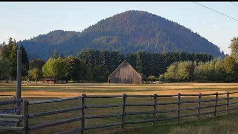 Rustic Wooden Barn and Split Rail Fence Below Forested Hill Mount Rainier. 스톡 동영상 343760736
