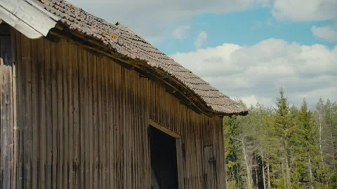 Rustic Wooden Barn Exterior With Forest Backdrop Beneath a Cloudy Blue Sky Stock Footage 335460153