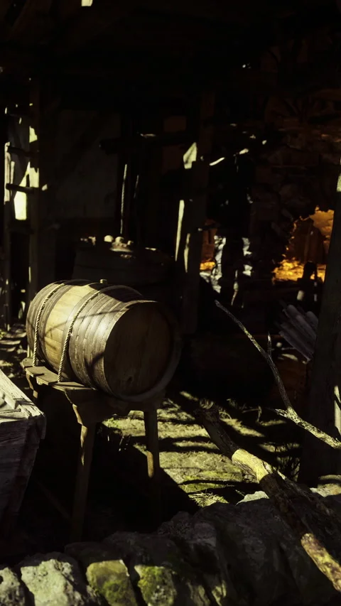 Rustic wooden barrel resting in an old barn filled with shadows and history Stock Footage 331809790