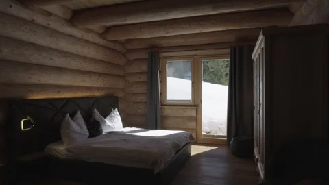 Rustic wooden bedroom interior with sunlight on the bed and snow outside the Stock-Footage 335756848