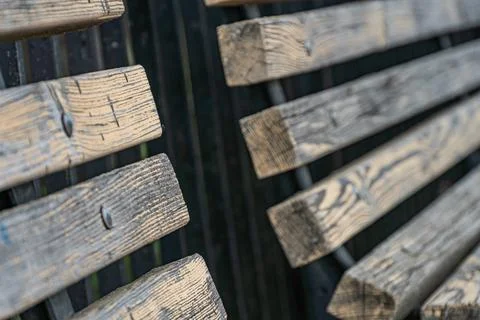 Rustic wooden bench in urban setting, contrasting with dark structure Weath.. Stock Photos