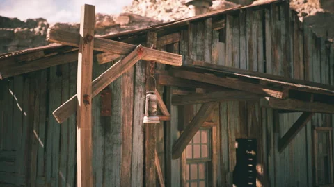 Rustic wooden building with lantern in a remote desert setting during daylight Stock Footage 304460424