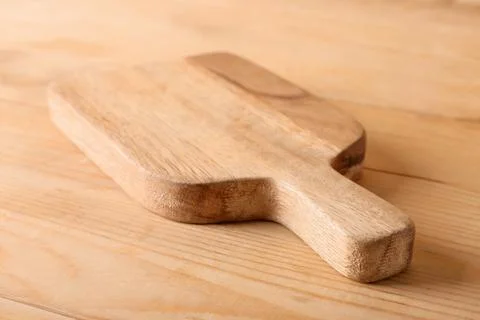 Rustic wooden cutting board with handle on a natural wood table, kitchen uten Photos