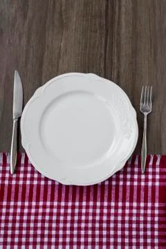 Rustic wooden dining table  with red napkin,white plate and cutlery set Stock Photos