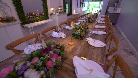 Rustic wooden dinner table with flowers, plates and gold lamps Stock Footage 345548875