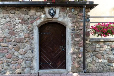 A rustic wooden door with diagonal patterns, heavy locks, and a lantern above Foto stock