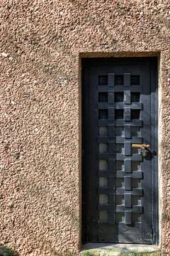 Rustic wooden door with waffle pattern panel, vintage stone wall facade Foto stock