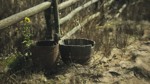 Rustic wooden fence with weathered buckets by a dusty path in nature Stock Footage 330069341