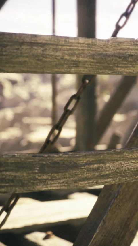 Rustic wooden frame reveals a weathered chain under the warm afternoon light Stock Footage 331834572