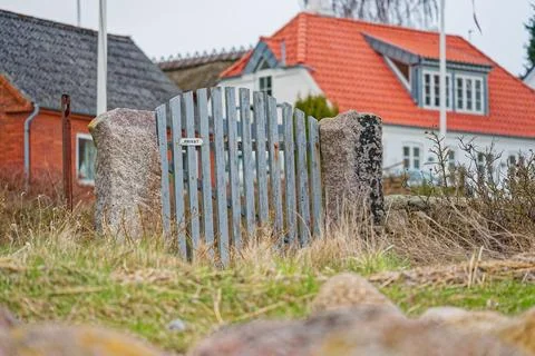 Rustic wooden gate between stone pillars in front of traditional houses wit.. Stock Photos