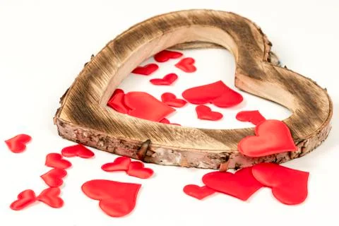 Rustic wooden heart filled and surrounded with small red hearts. Love concept. Stock Photos