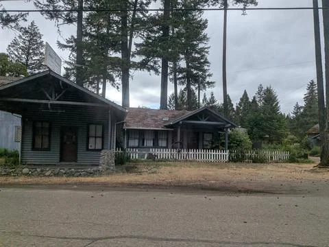 A rustic wooden log building with a white picket fence and a vintage sign Stock Photos